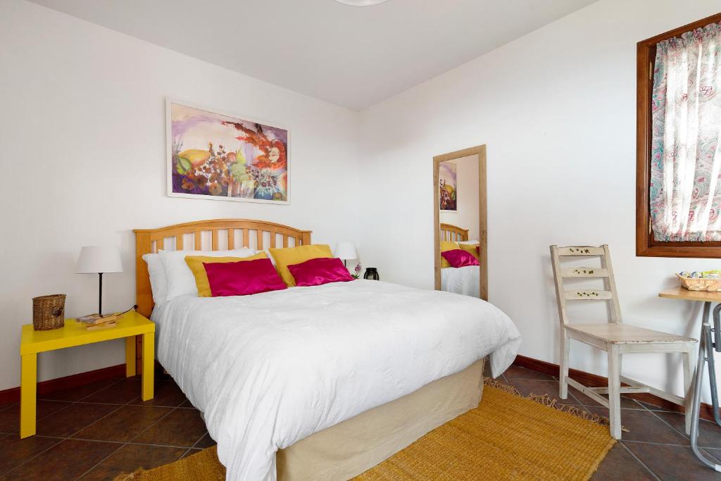 um quarto com uma grande cama branca com almofadas vermelhas em La Casita Canaria em Los Silos