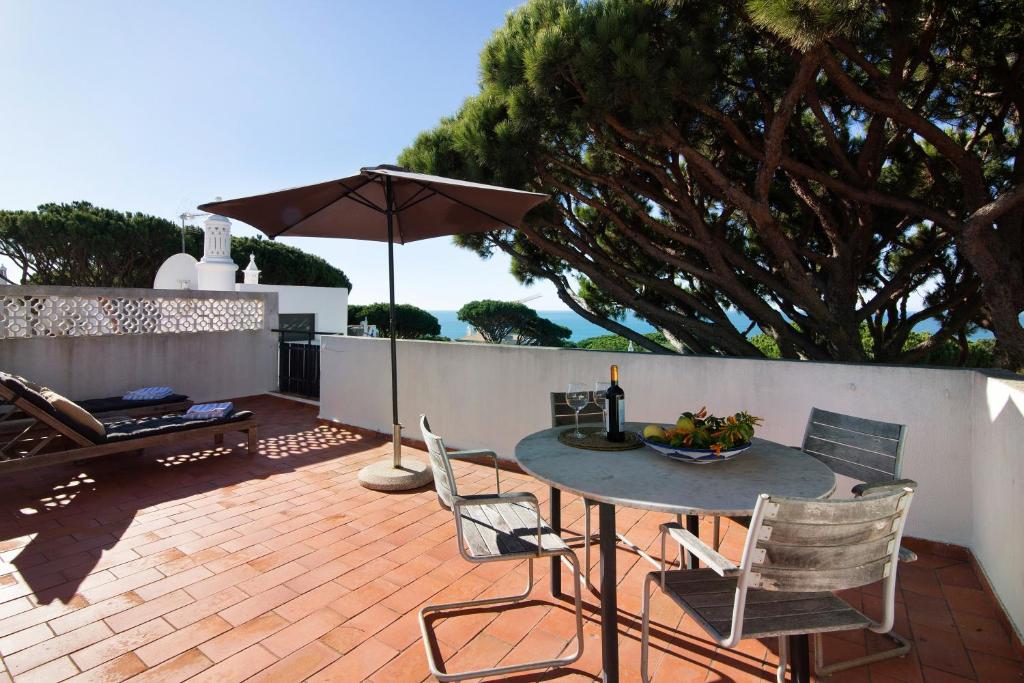 a patio with a table and chairs and an umbrella at Casa Allan in Vale do Lobo