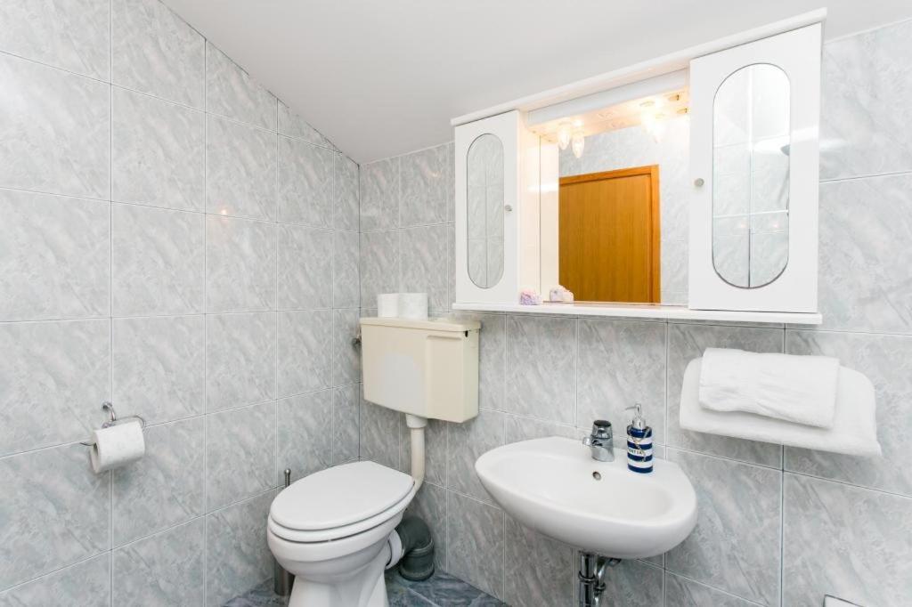 een badkamer met een toilet, een wastafel en een spiegel bij Apartments Laura Mljet in Sobra