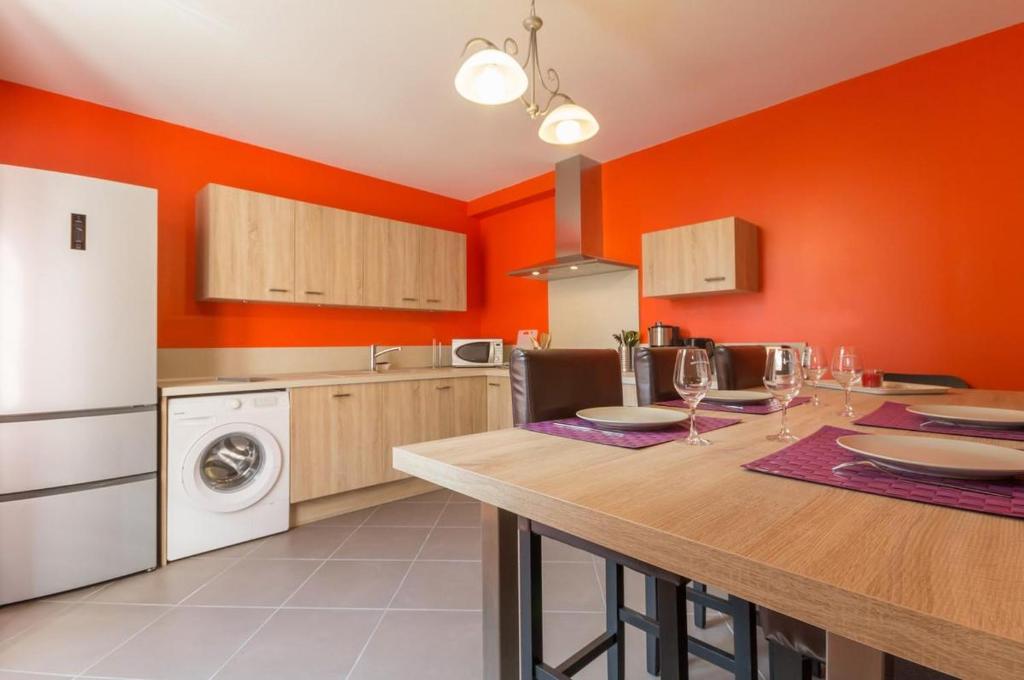 a kitchen with orange walls and a table with wine glasses at Chez Germaine in Saint-Romain