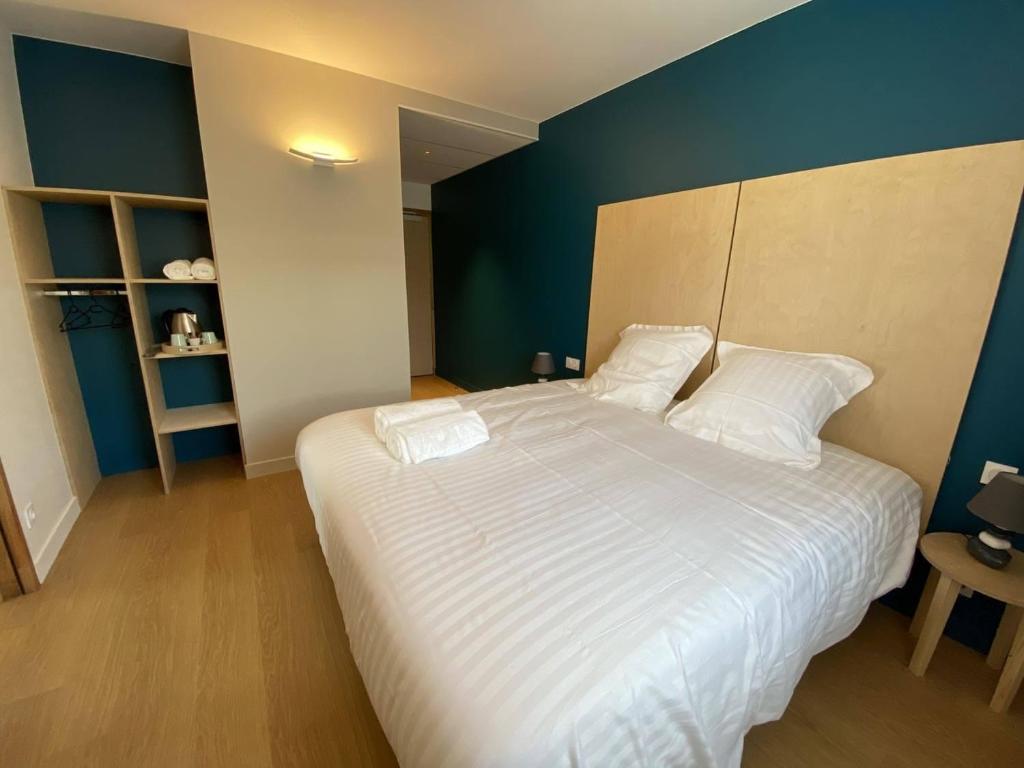 a bedroom with a large white bed with blue walls at CHEZ MAMITA in Landivisiau
