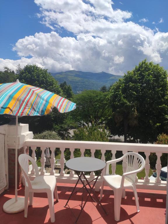 un tavolo e sedie su un balcone con ombrellone di Studio avec terrasse vue Tourmalet dans Villa historique "Victoria" ad Argelès-Gazost