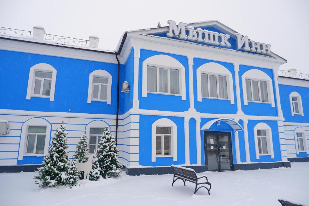 um edifício azul com árvores de Natal em frente em Guest center-hotel Myshk Inn em Myshkin