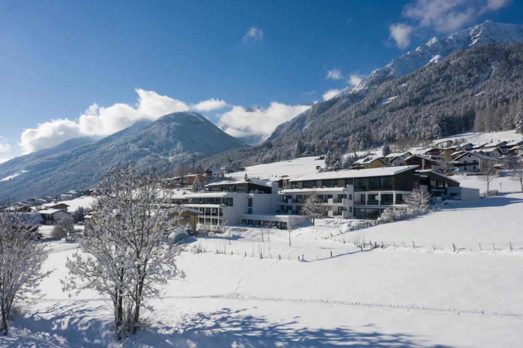 a resort in the snow with a mountain in the background at Hotel & Appartements Oberhofer in Telfes im Stubai
