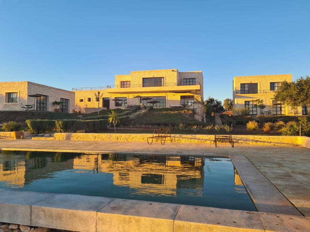 una piscina d'acqua di fronte ad alcuni edifici di Tassourt Lodge a Essaouira