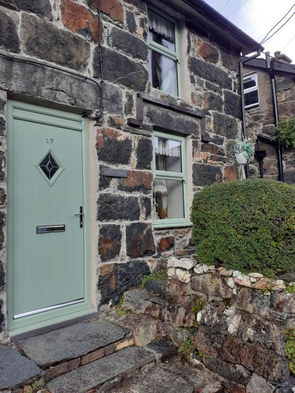 una casa in pietra con una porta bianca e due finestre di bryn cilio a Beddgelert
