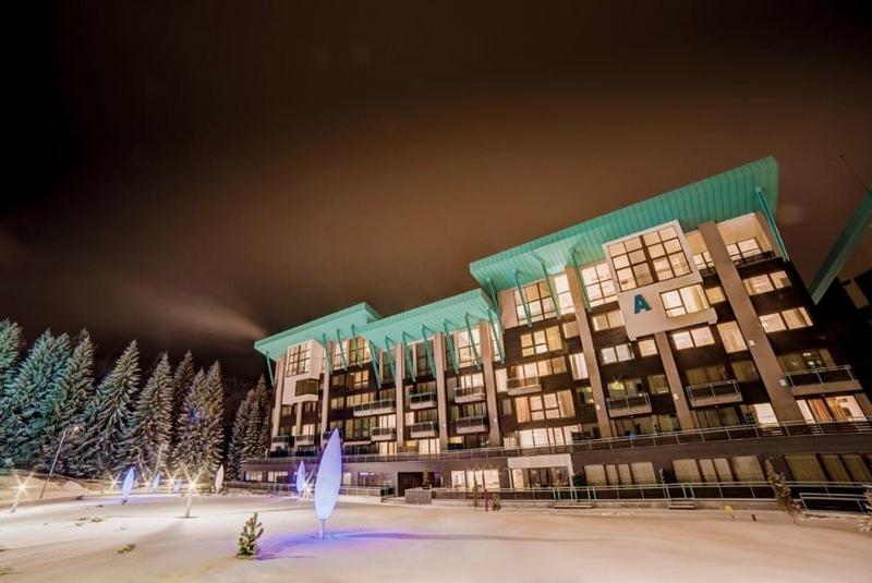a large building in the snow at night at Pine Woods Apartment B35 in Silver Mountain in Poiana Brasov