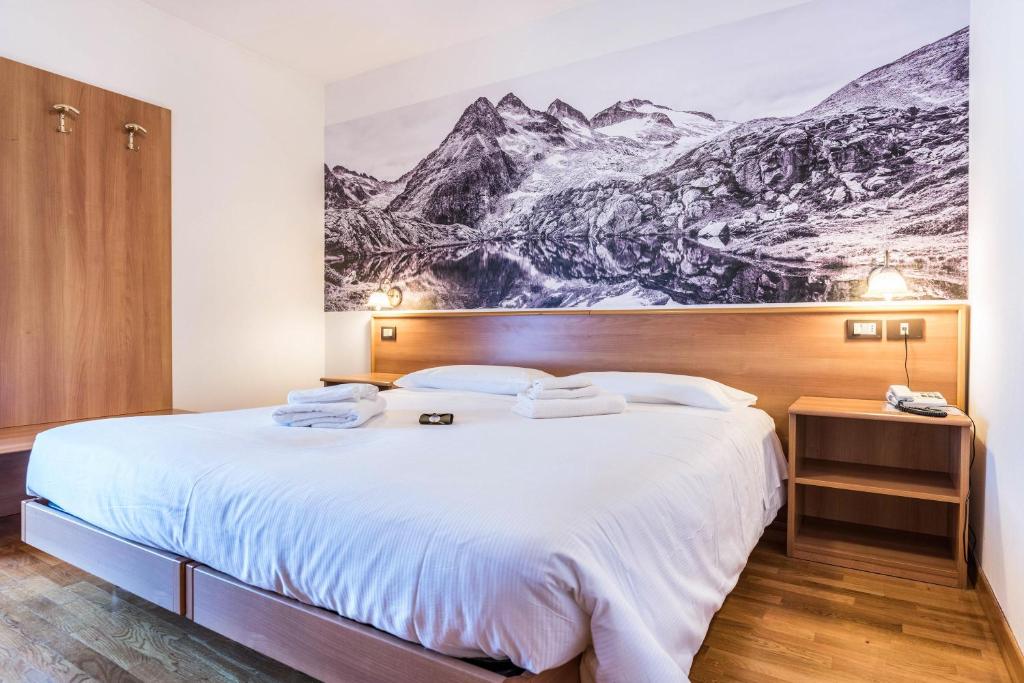 ein Hotelzimmer mit einem großen Bett mit einem Wandbild der Berge in der Unterkunft Residence Park Imperator Quadri in Carisolo