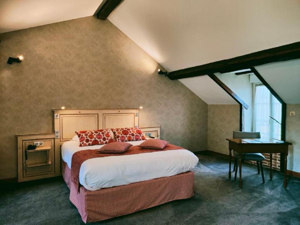 ein Schlafzimmer mit einem großen Bett und einem Schreibtisch in einem Zimmer in der Unterkunft La Chaumière in Aubigny-sur-Nère
