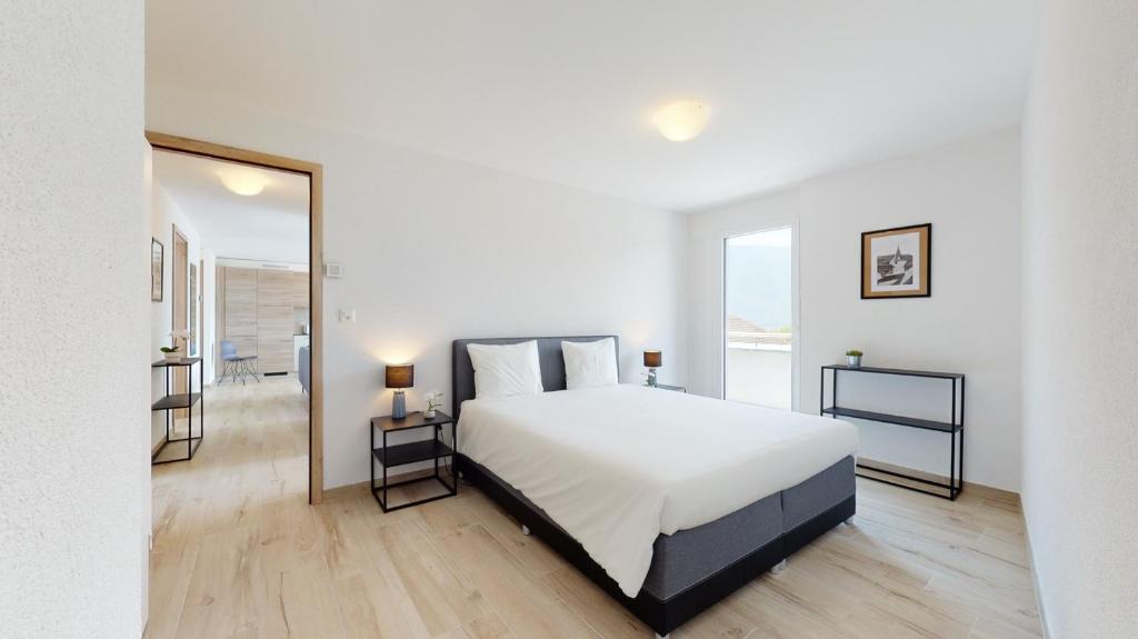 1 dormitorio con 1 cama grande y espejo grande en Nonanteneuf Appart-hôtel - Aigle, en Aigle