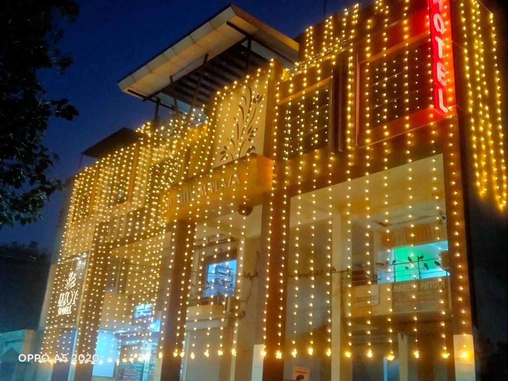 a building with lights on the side of it at Lijoy Hotel & Restra in Būndi