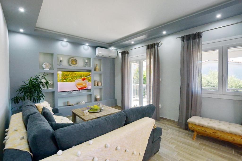 sala de estar con sofás azules y TV en Blue North Luxury Apartment, en Limenas