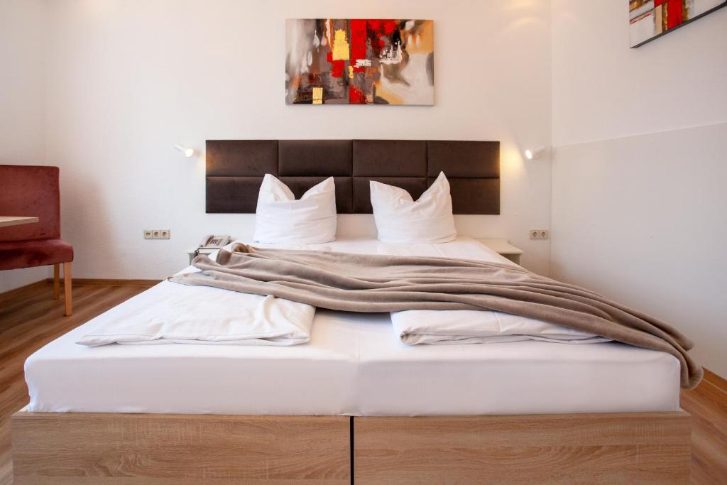 a bedroom with a large white bed with a wooden headboard at Relax Hotel & SPA Stuttgart in Stuttgart