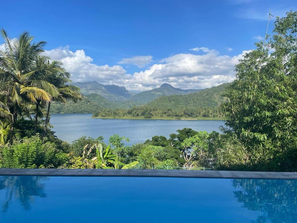 uma piscina com vista para um lago em The Glasshouse Victoria Villa, Kandy em Digana