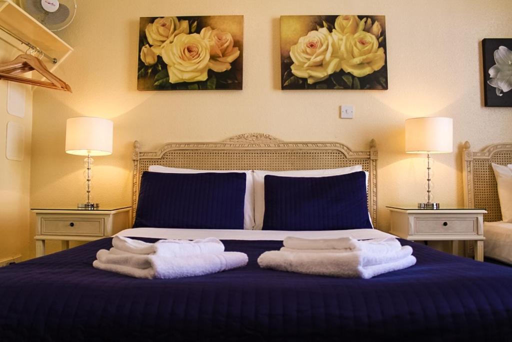 um quarto com uma cama azul com toalhas em Blades Hotel em Londres