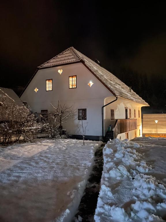 una casa con luces encendidas en la nieve por la noche en Juvanova hiša (all house), en Luče
