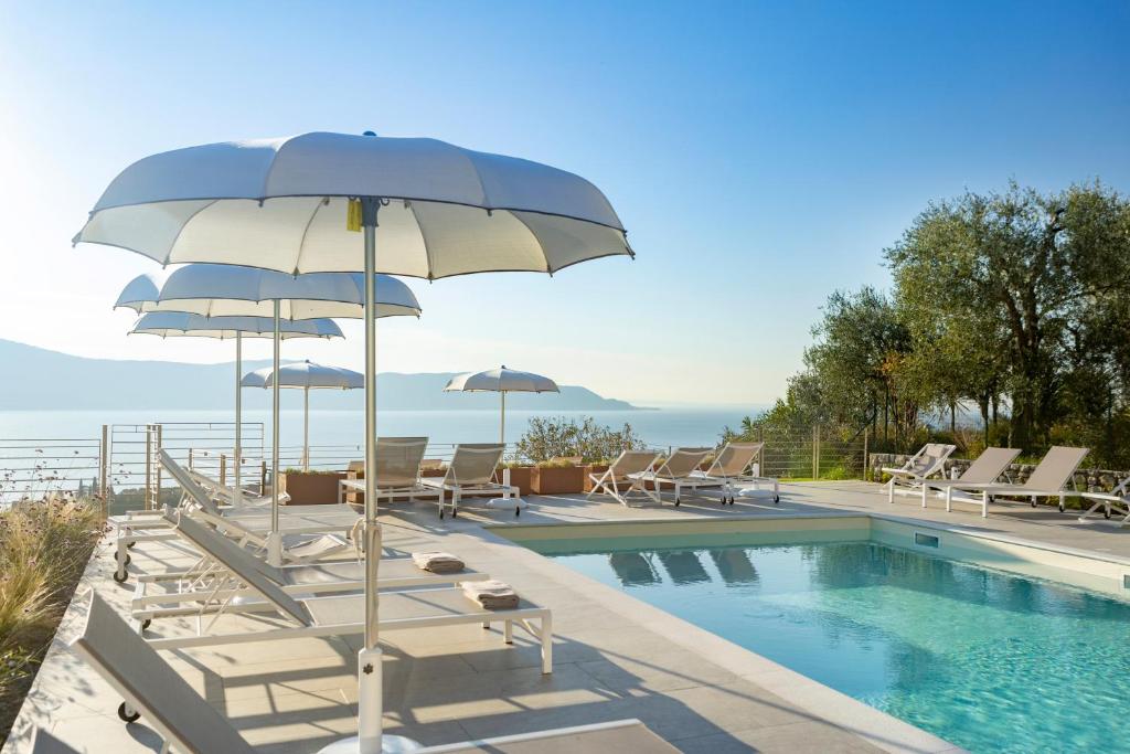 a swimming pool with chairs and umbrellas next to a swimming pool at Relais Zenner in Toscolano Maderno