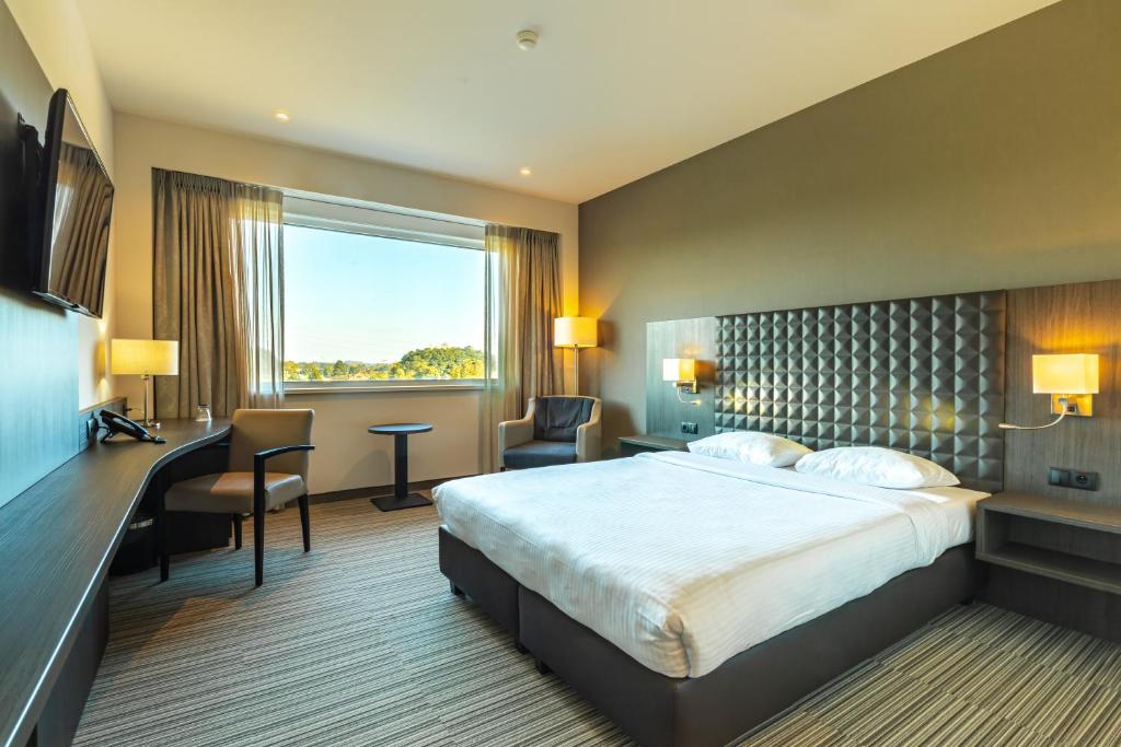 
a hotel room with two beds and a large window at Mezzo Hotel & Business in Beringen
