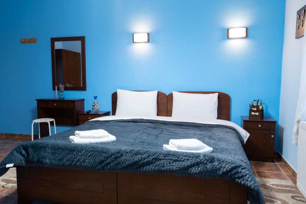 a blue bedroom with a bed with two towels on it at Ξενώνας Αντωνία in Kato Loutraki