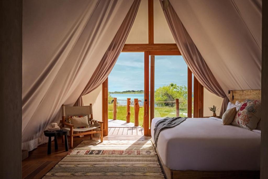 a bedroom with a bed and a view of the water at Our Habitas Bacalar in Bacalar