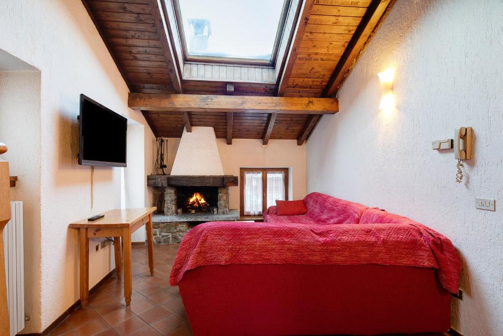 a bedroom with a red bed and a fireplace at Chalet Meridiana Appartamento 9 in Livigno