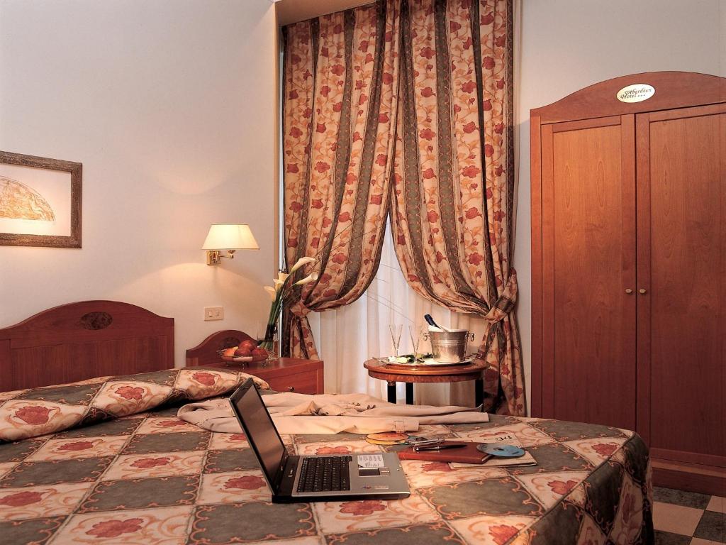 a bedroom with a bed and a desk with a laptop at Hotel Aberdeen in Rome