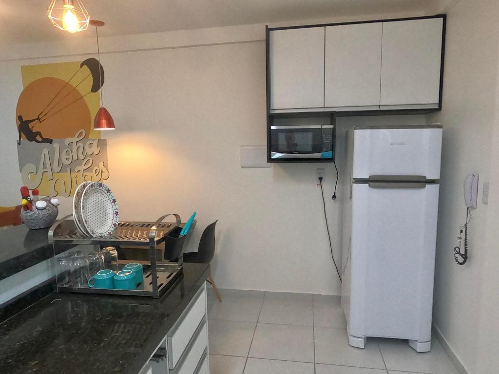 a kitchen with a white refrigerator and a microwave at Aloha Vibes Ap Cumbuco - Green Club in Cumbuco