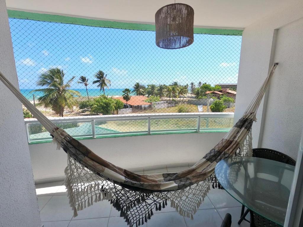 a hammock on a balcony with a view of the beach at Aloha Vibes Ap Cumbuco - Green Club in Cumbuco