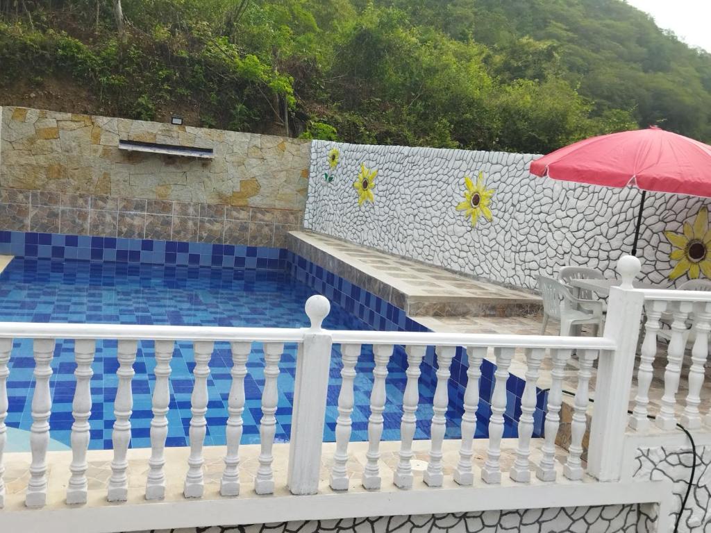 einen Pool mit einem weißen Zaun und einem Regenschirm in der Unterkunft FINCA CAMPESTRE EL MIRADOR VIOTA in Viotá