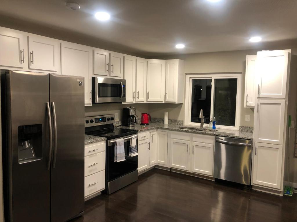 a kitchen with white cabinets and stainless steel appliances at MileHi Vacation Home in Aurora