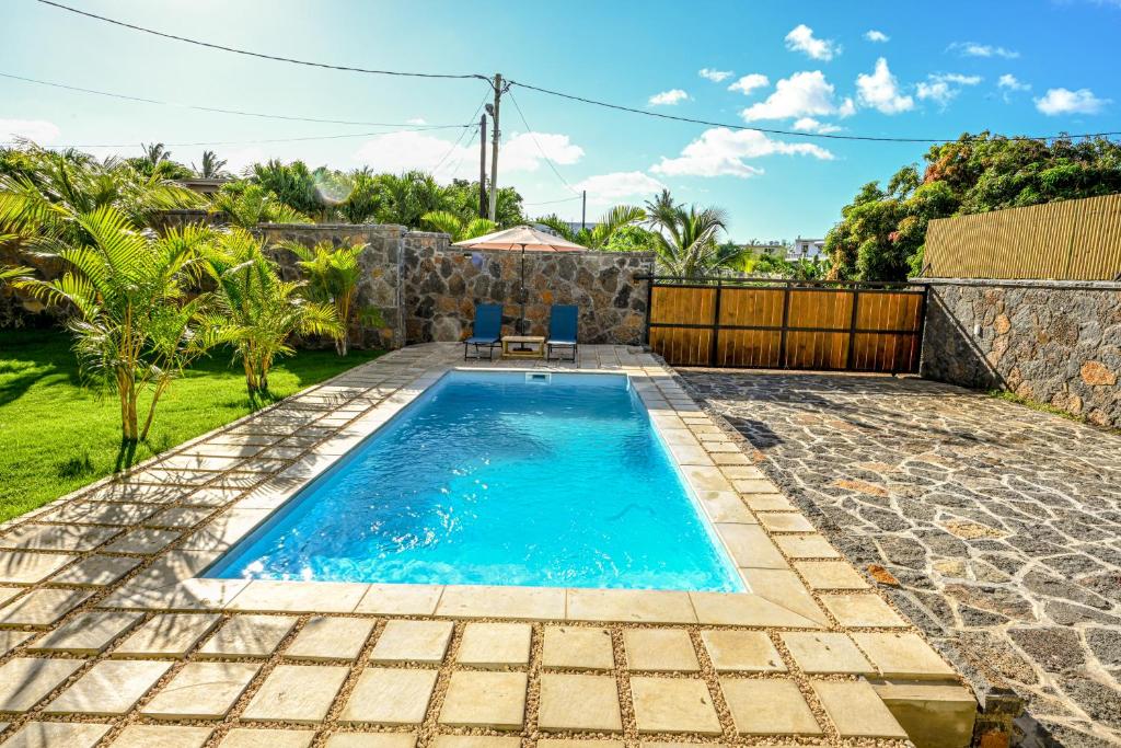 uma piscina com duas cadeiras num quintal em New Villa Geranium em Grand Baie