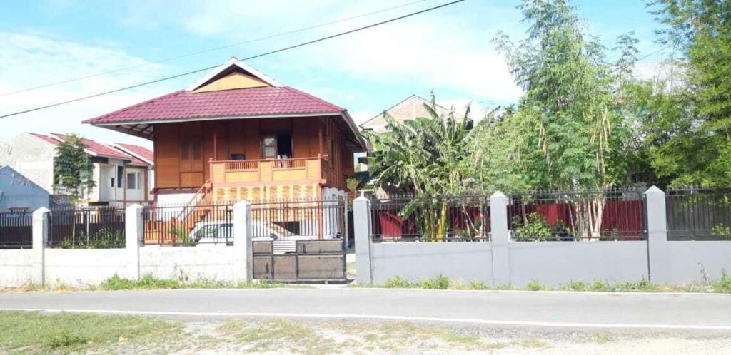 a house with a white fence and a house with a gate at Comfortable Great and Cheap in Palu