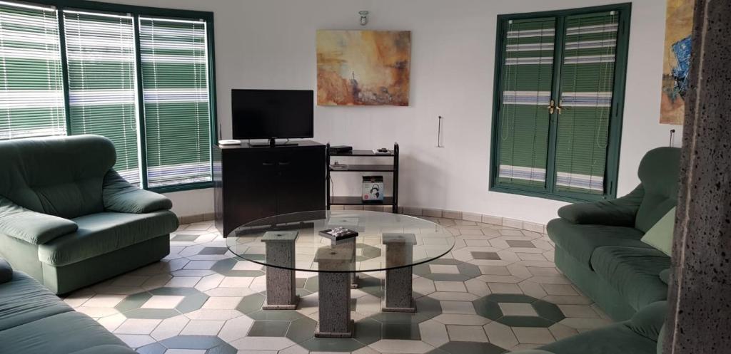 sala de estar con 2 sofás y mesa de cristal en Villa Los Ojos, en Charco del Palo