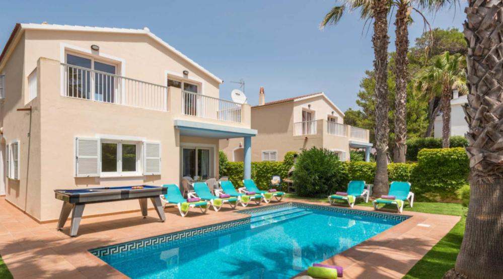 a villa with a swimming pool and blue chairs at Villas Serena in Cala Blanca