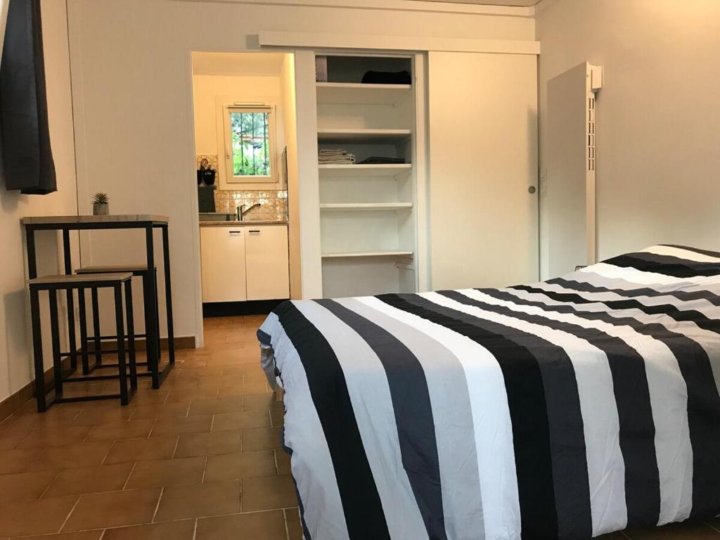- une chambre avec un lit rayé noir et blanc et une table dans l'établissement Appartement Rez de villa - Porte des Calanques, à La Redonne