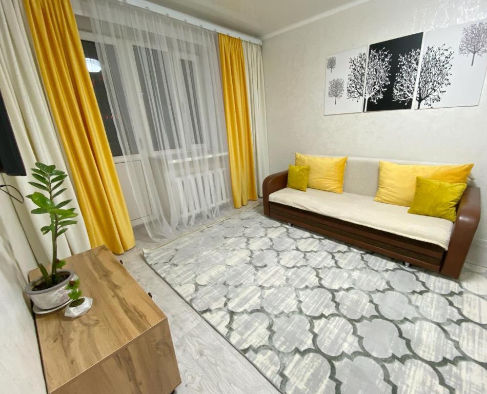 a living room with yellow curtains and a couch at Апартаменты на Ахметова 6 in Turksib