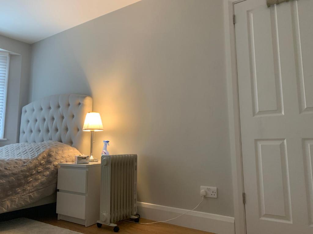 a bedroom with a bed and a lamp on a night stand at Immaculate 4 bedroom house Near central London in Edgware