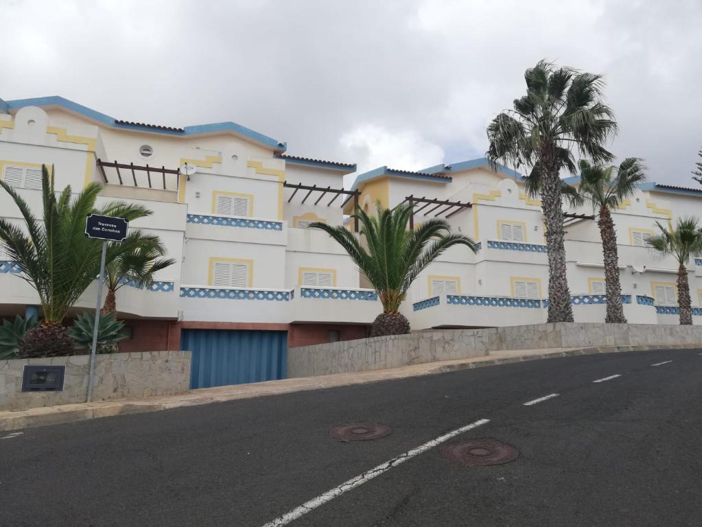 un edificio con palmeras frente a una calle en Apartamento Pedras Pretas en Porto Santo