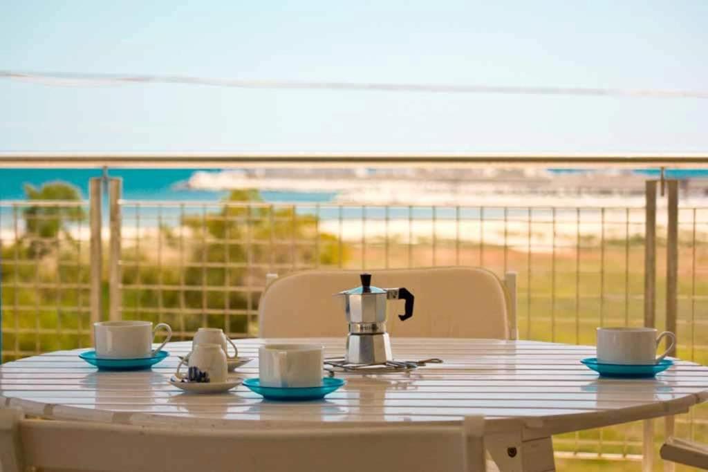 a table with a coffee pot and cups on a balcony at Casa Serra in Porto Palo