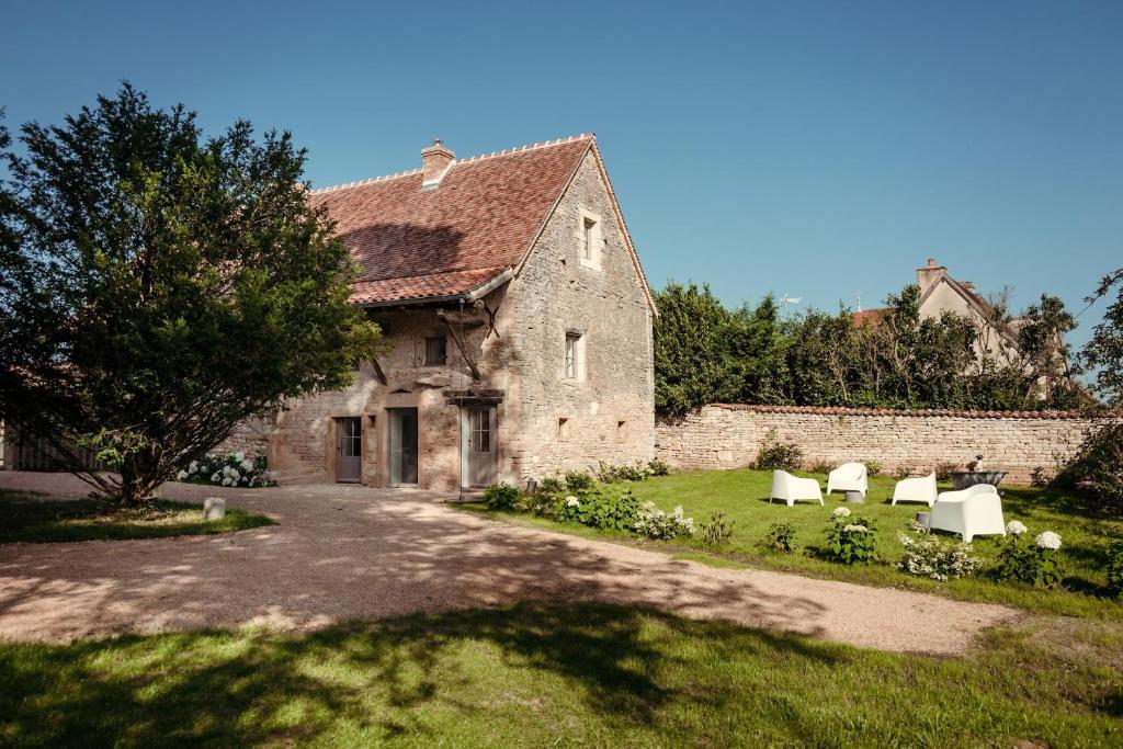 - un vieux bâtiment en pierre avec des chaises dans une cour dans l'établissement Clos des Dames de Lancharre, à Chapaize