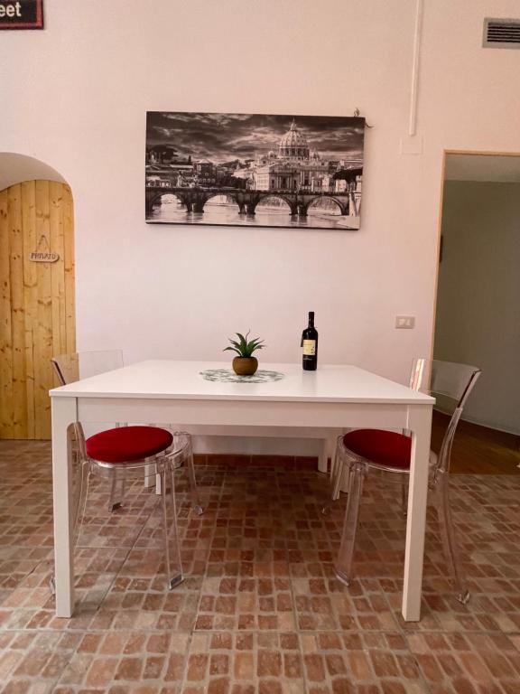 - une table blanche avec une bouteille de vin et 2 chaises dans l'établissement Appartamento Stazione Termini, à Rome
