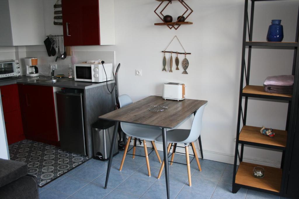 a small kitchen with a wooden table and chairs at escapade en mer in Ault