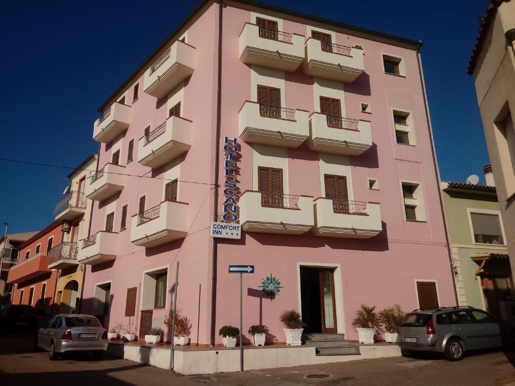 un bâtiment rose avec des voitures garées devant lui dans l'établissement Scano Comfort Inn, à Santa Teresa Gallura