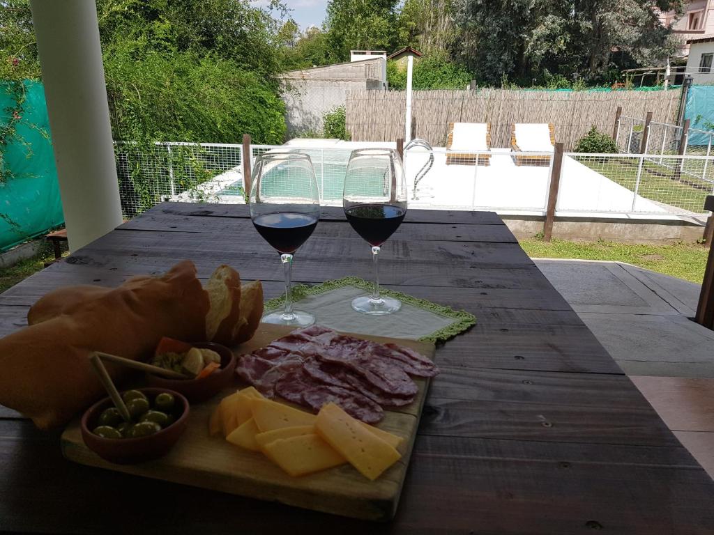 una mesa con dos copas de vino tinto y queso en Cabaña La Antonia 1 en La Granja