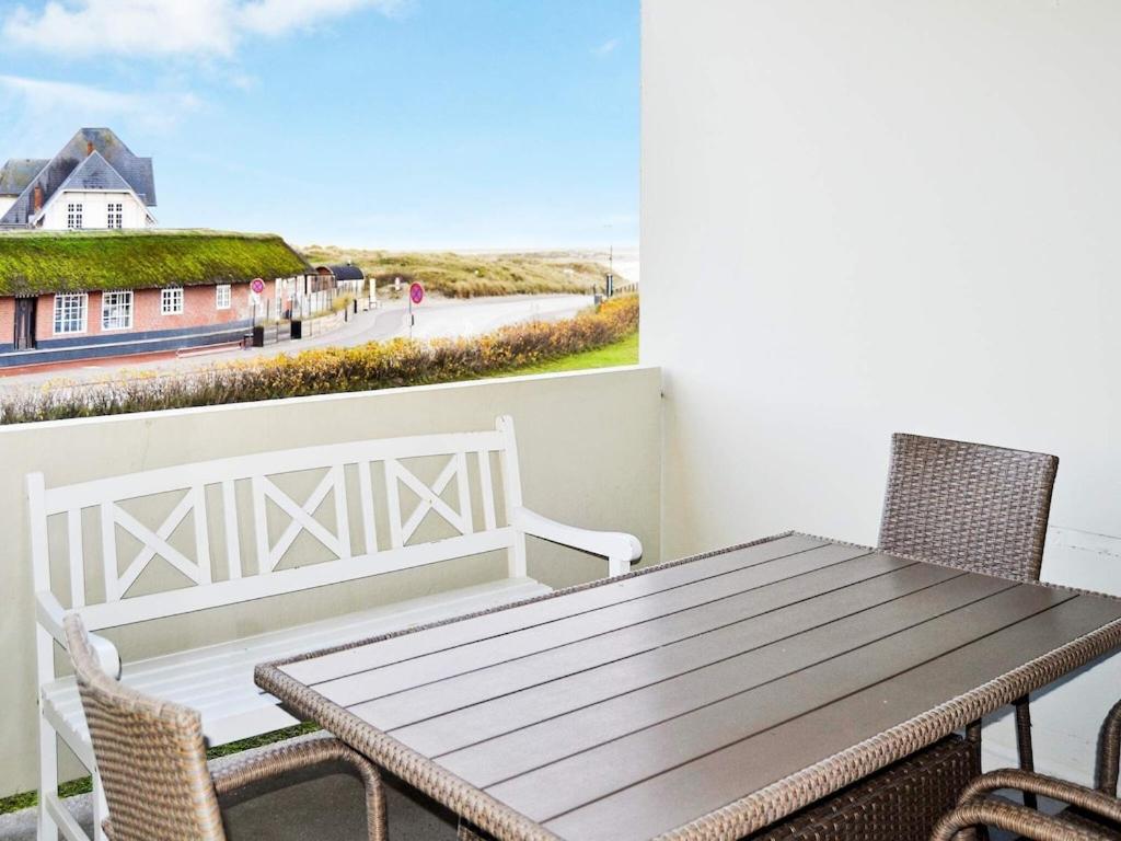 una mesa de madera y sillas en un balcón con vistas al océano en 4 person holiday home in Fan en Fanø