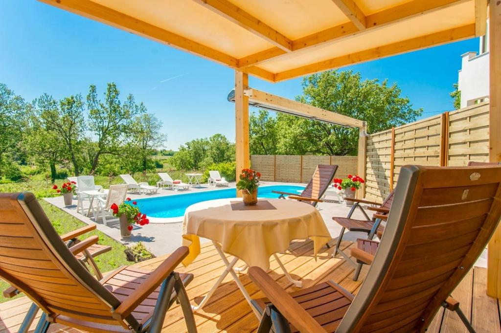 patio ze stołem i krzesłami oraz basenem w obiekcie Apartments Marinko-with pool w mieście Barban