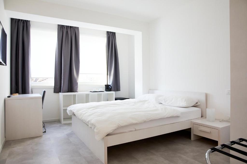 Dormitorio blanco con cama blanca y ventanas en Le Vette Room&Breakfast, en Rovereto