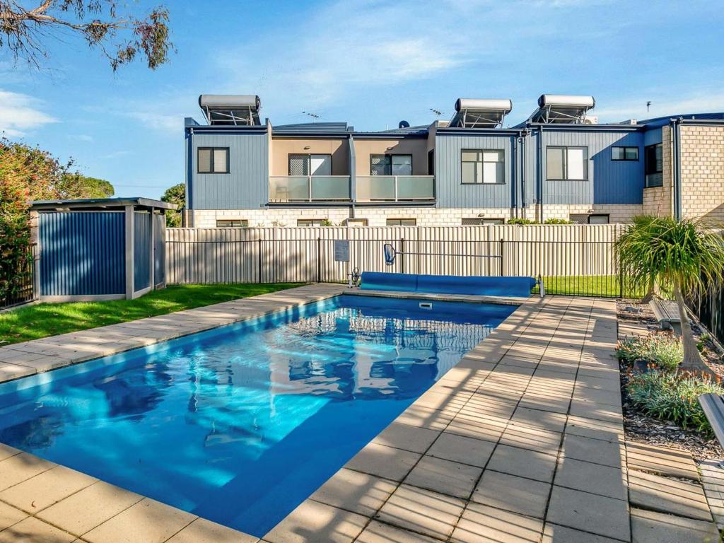 a house with a swimming pool in front of a fence at Starfish Sands in Cowes