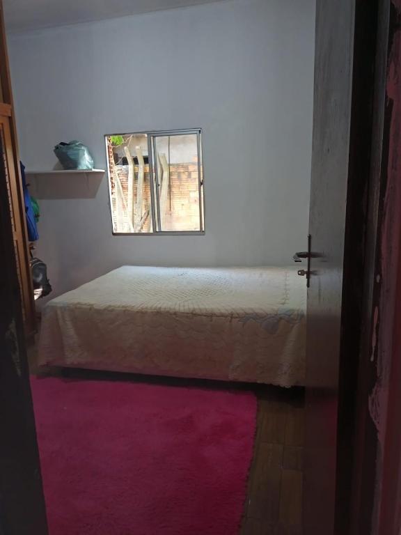 een slaapkamer met een bed met een raam en een roze kleed bij Casa de praia em torres in Torres