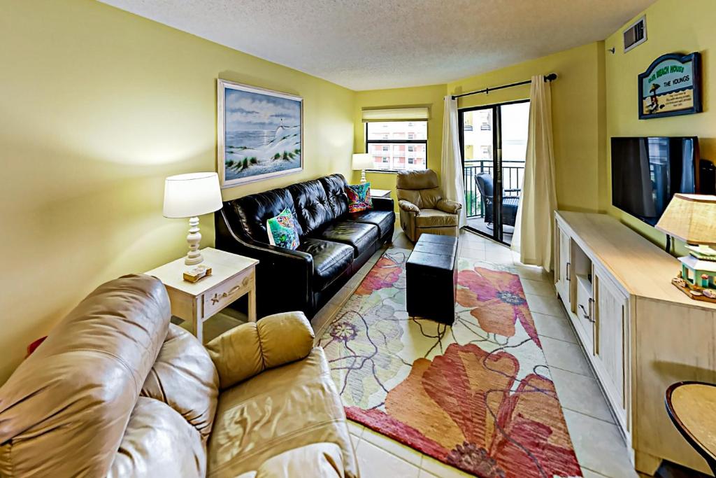 a living room with a couch and a tv at Vistas On The Gulf Unit 408 in St. Pete Beach